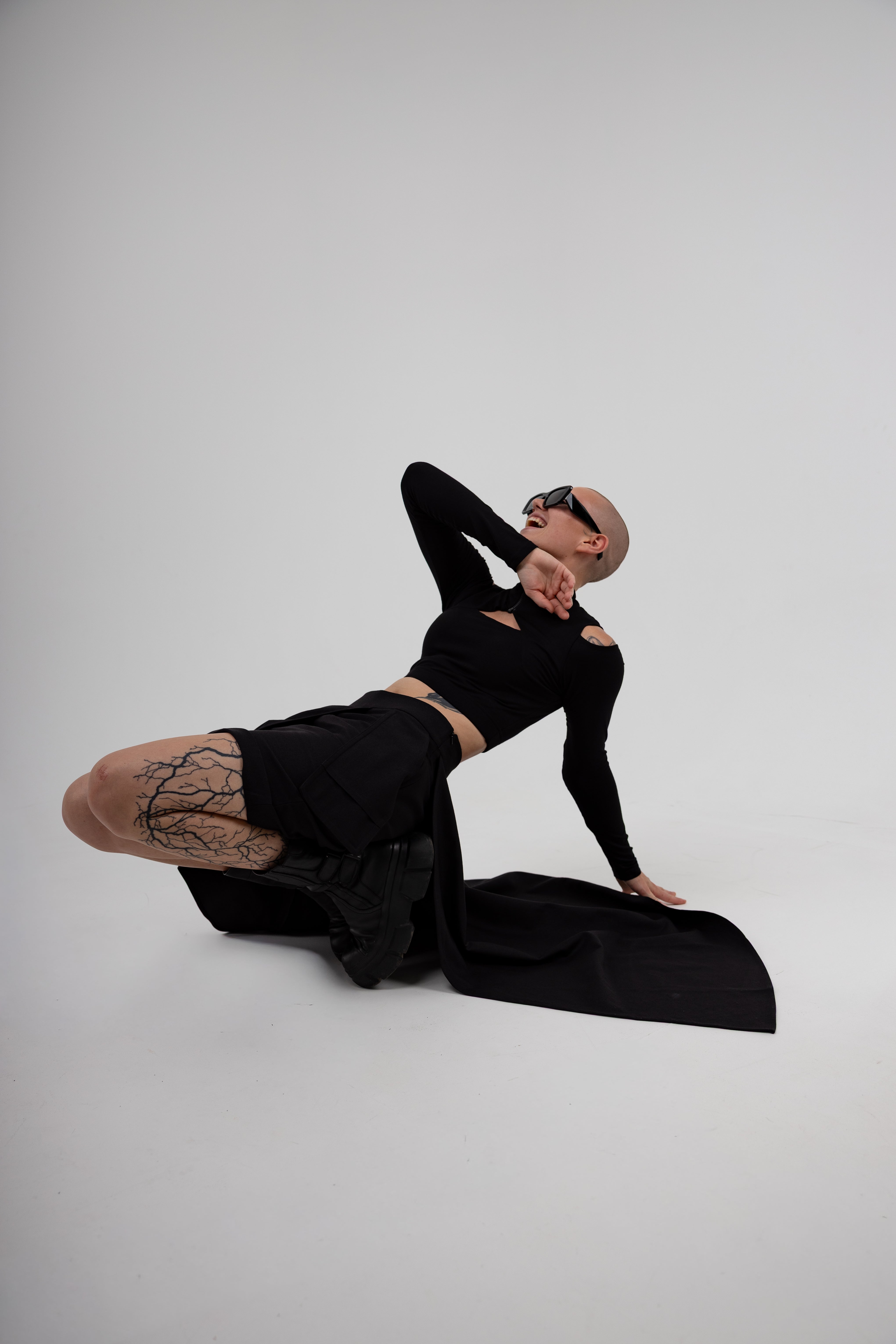Person wearing a black outfit with sheer stockings on a white background