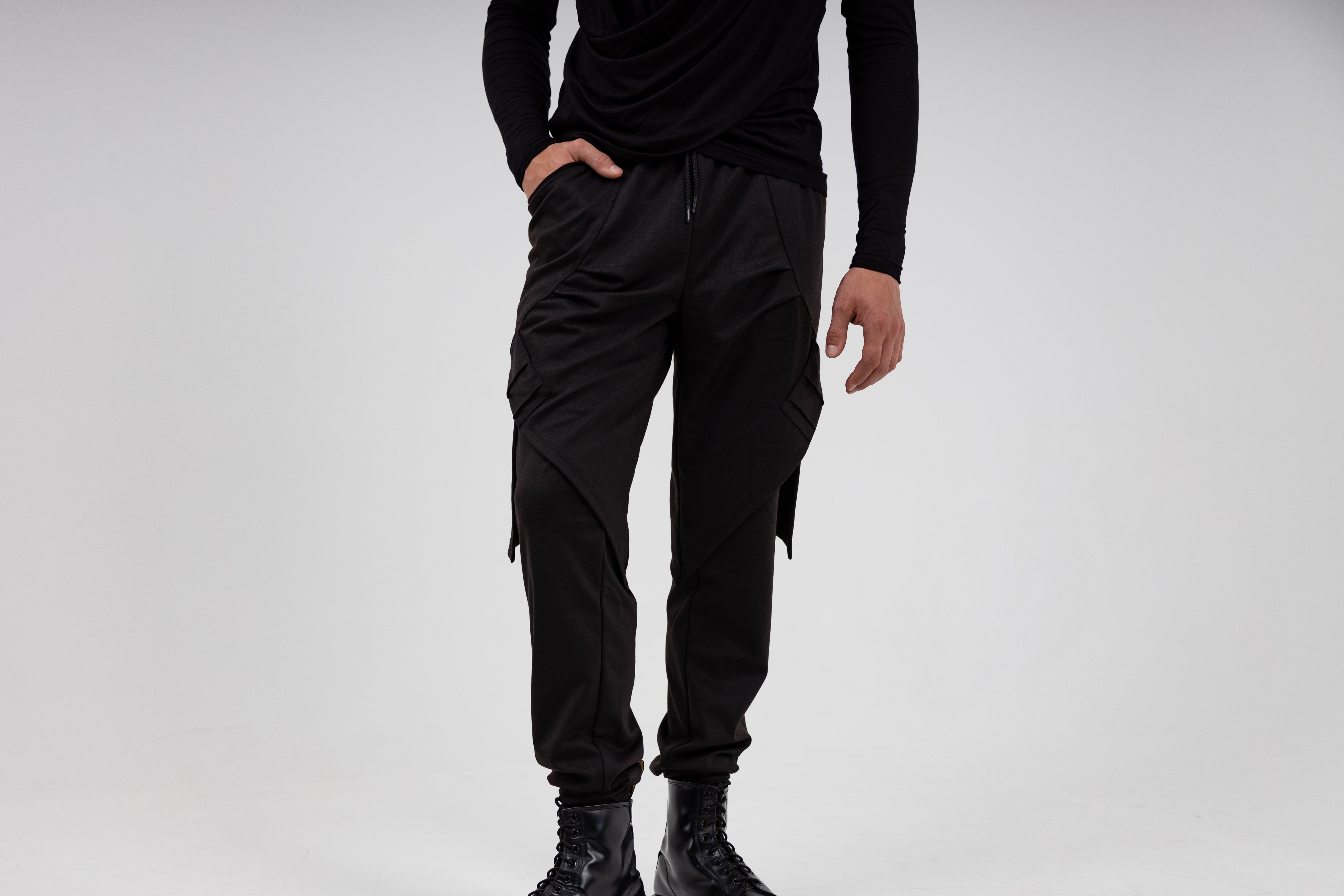 male Person wearing black jogger pants and black shoes on a light gray background