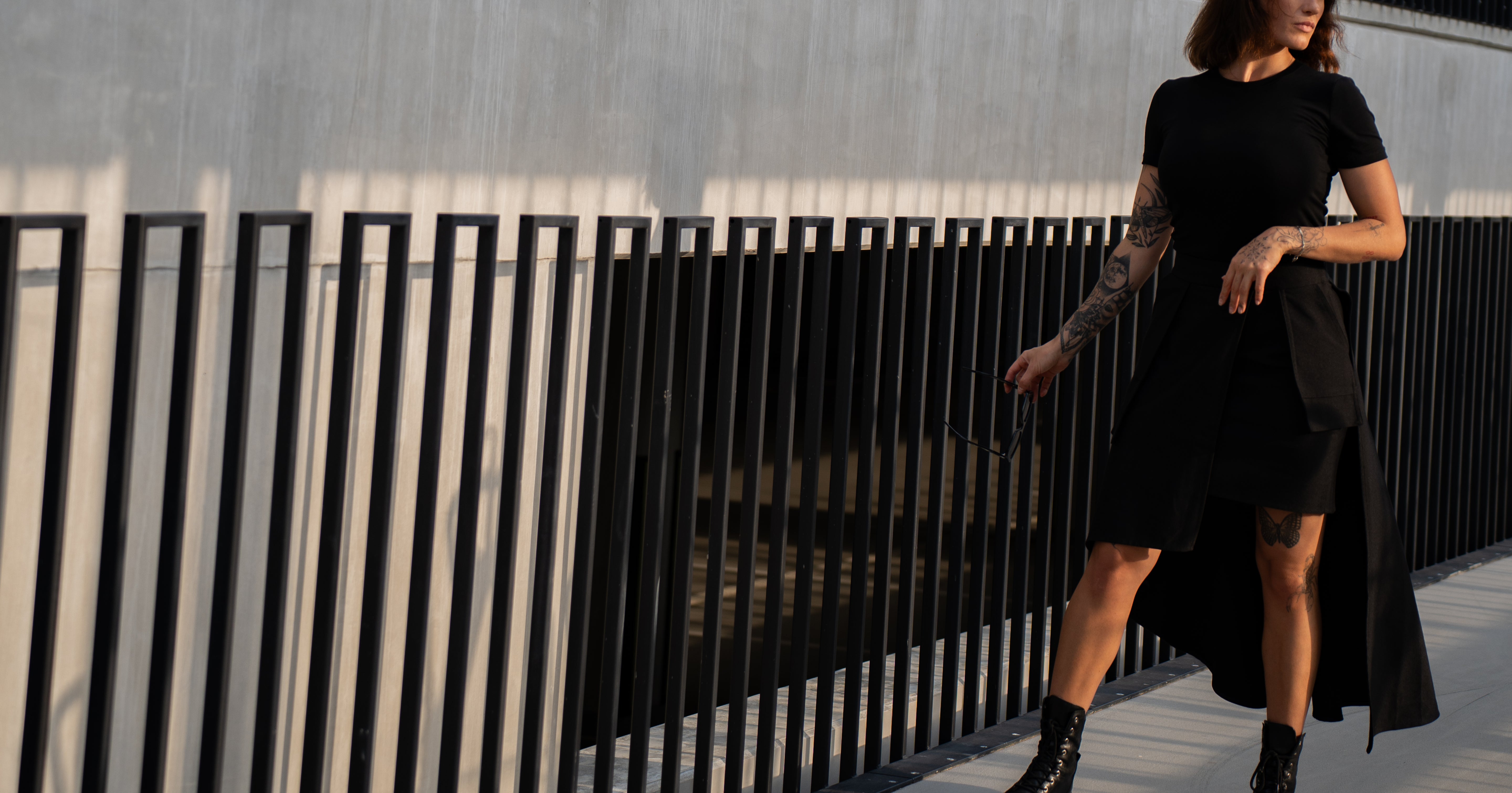 Woman in a black dress standing against a modern architectural background