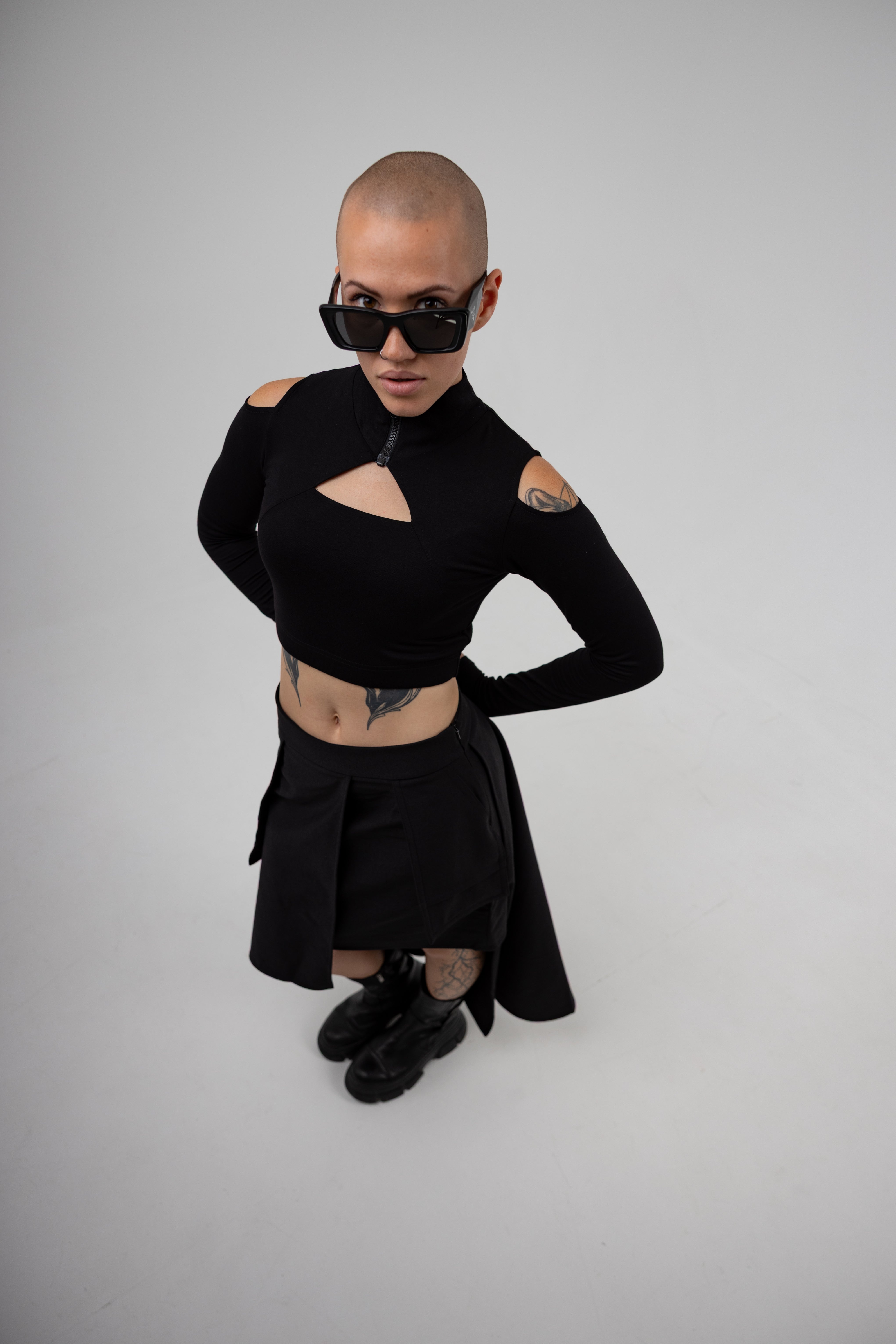 Person wearing a black outfit with cut-out design on a gray background