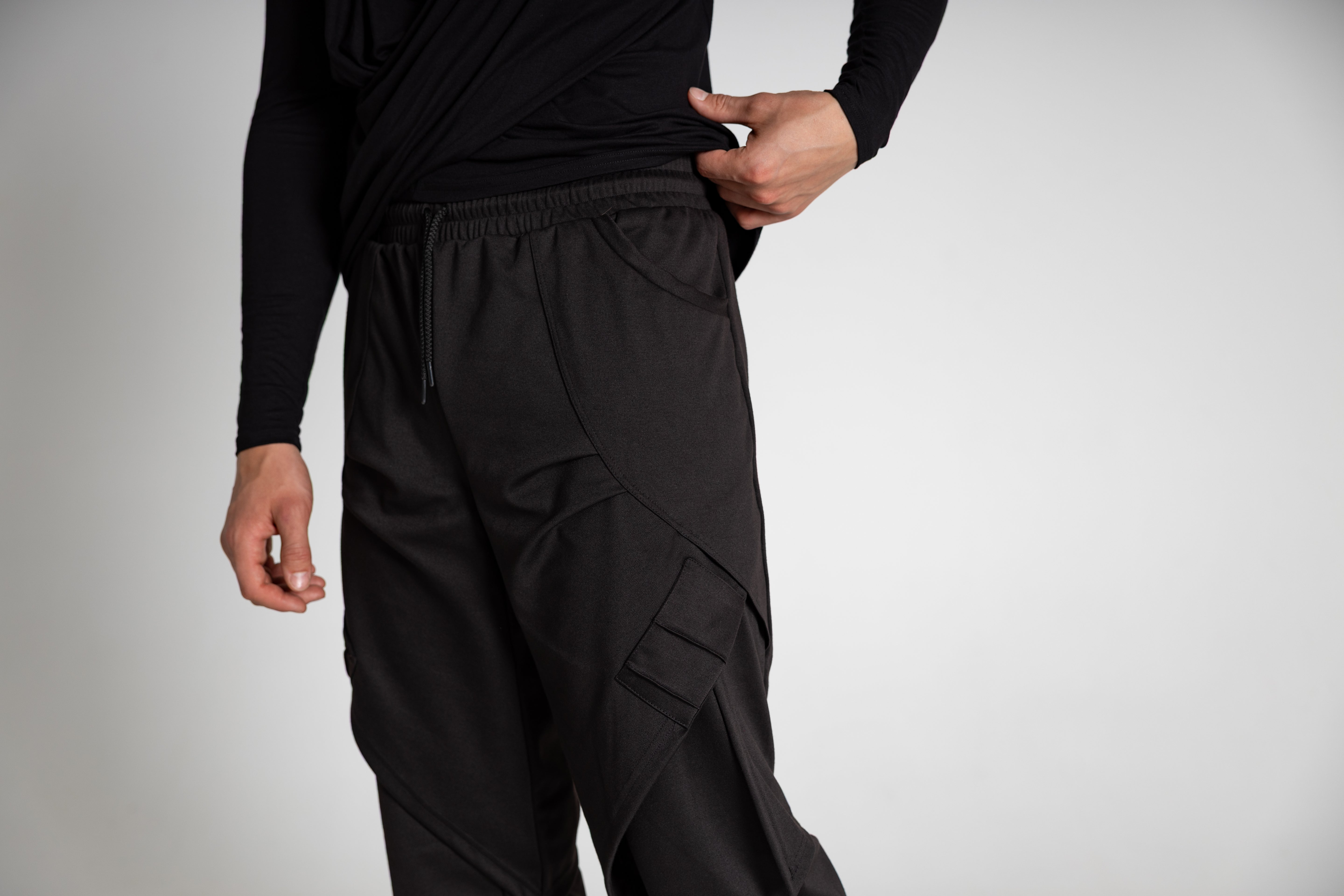 Person wearing black cargo pants on a plain background