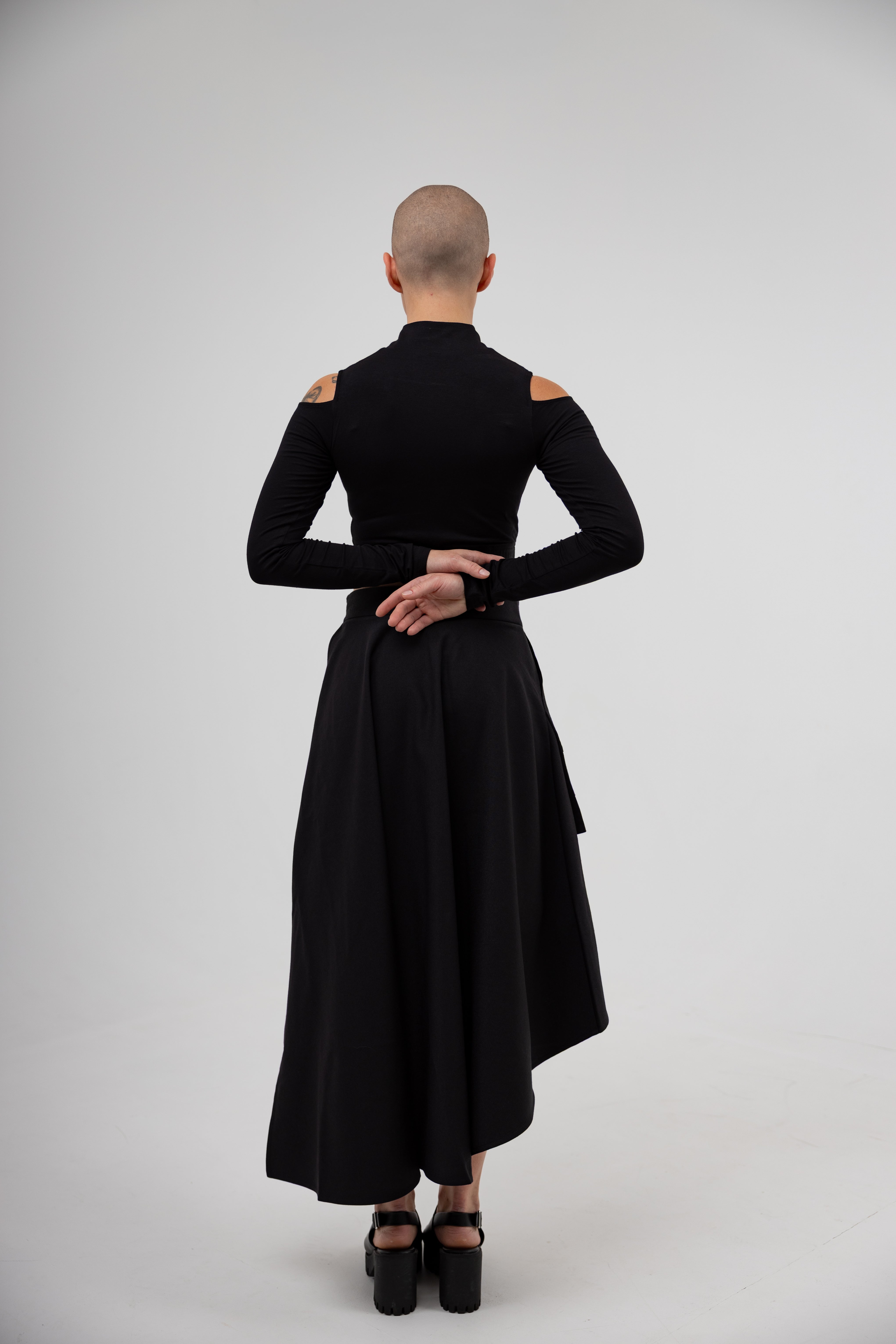 Person wearing a black dress with cut-out shoulders on a white background