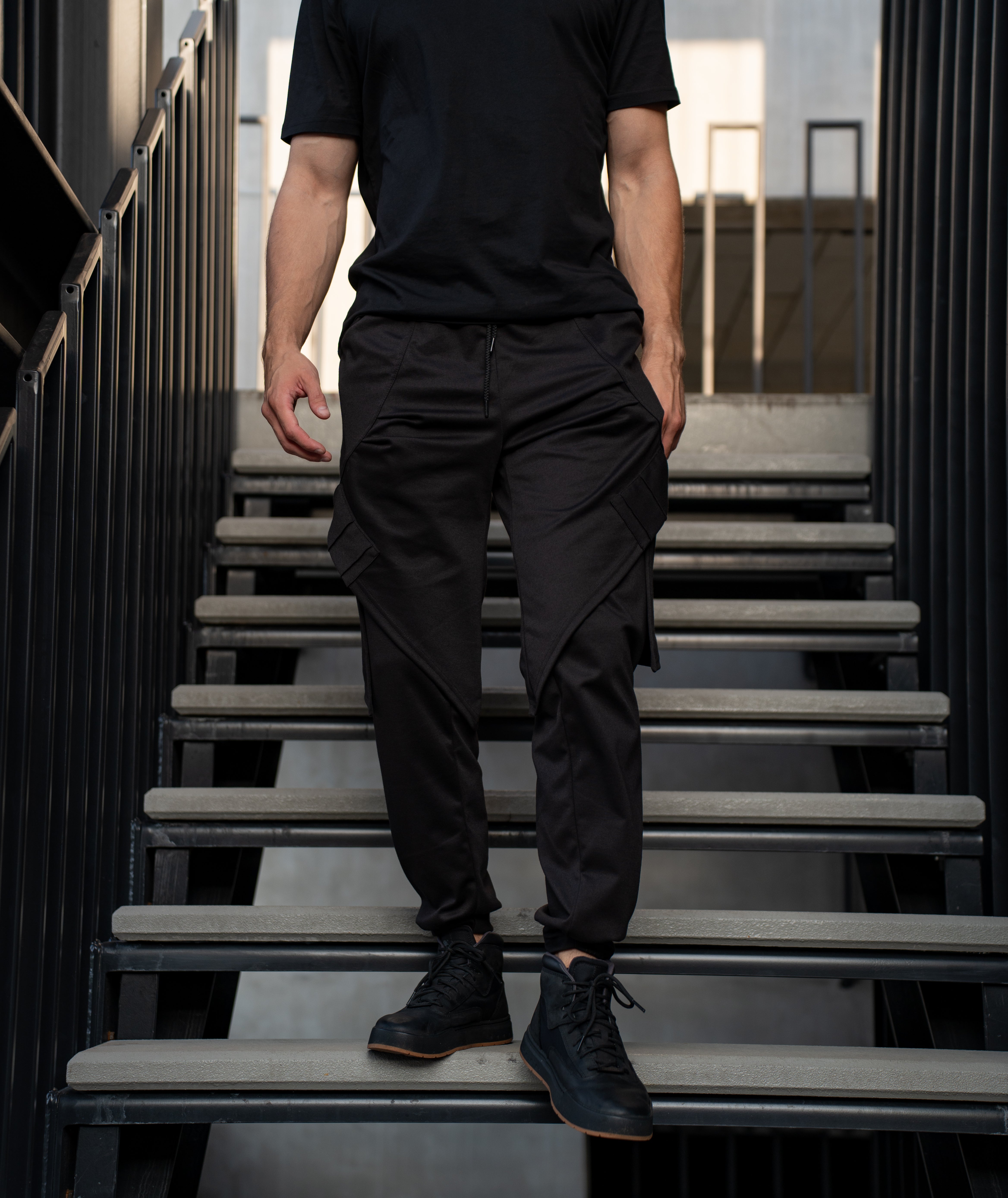 Person wearing black casual minimal streetwear outfit standing on stairs 