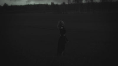 woman standing in green field with all black clothing