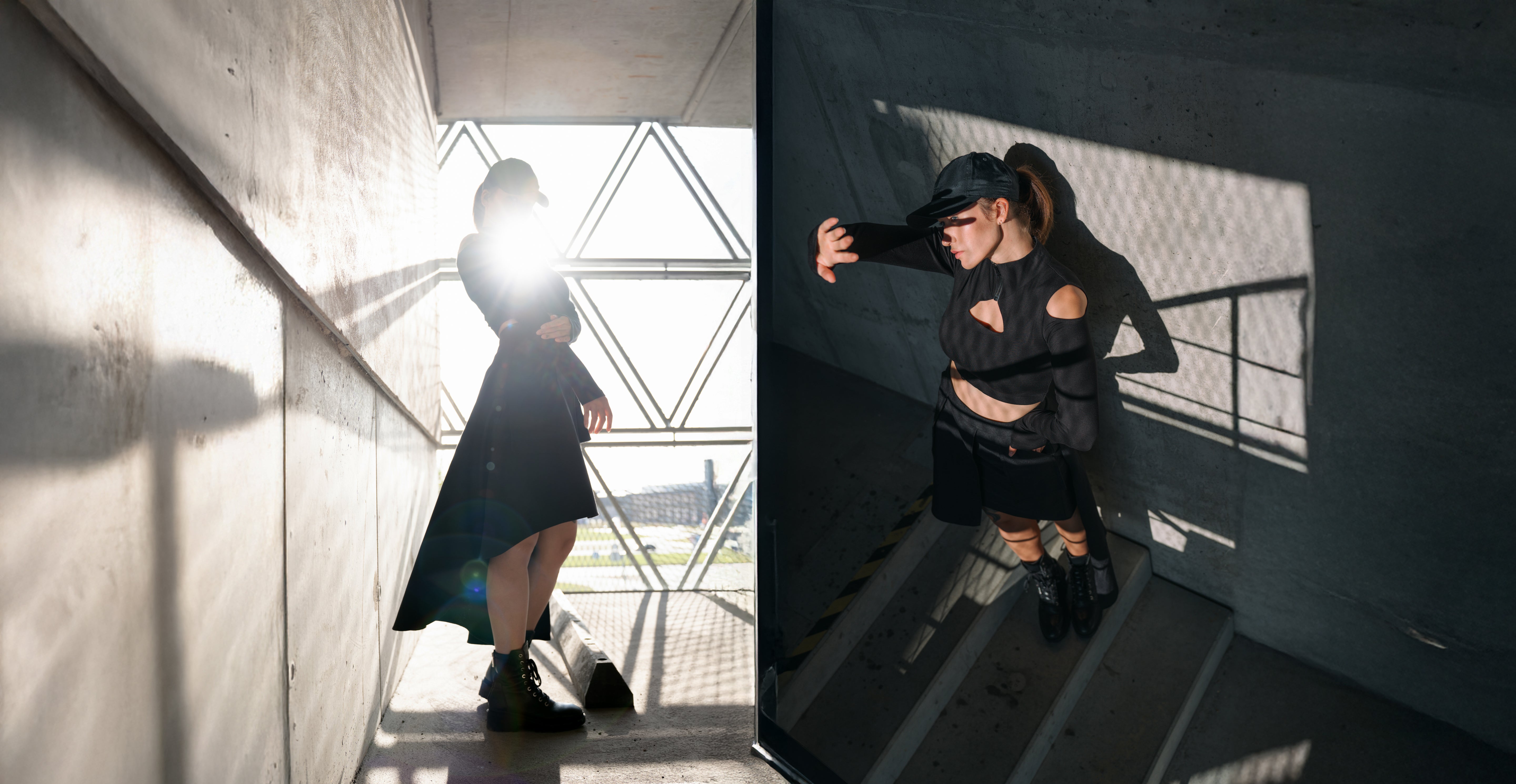 Person in a black outfit standing in a concrete structure with light and shadow play.